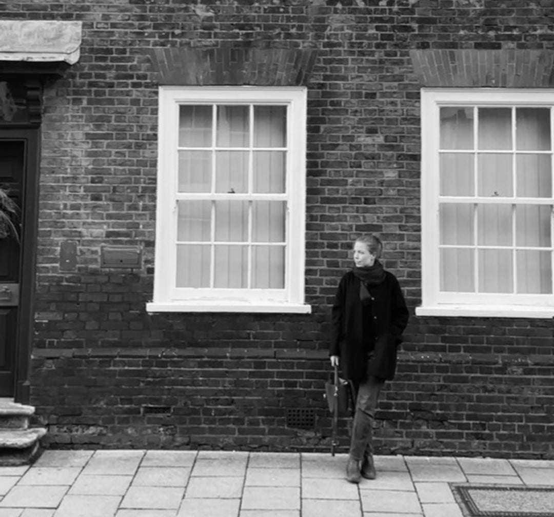 Erin, founder of Table & Sill, standing beside the sash windows of an old brick building